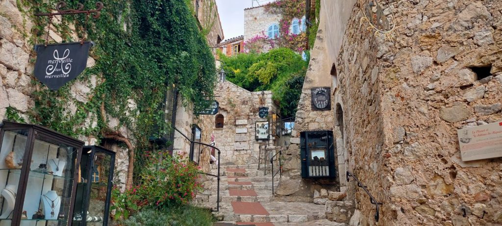 Malerische Altstadtgasse von Èze – eines der schönsten Ziele für Tagesausflüge ab Nizza, mit Kopfsteinpflaster, Steinmauern, Boutiquen und Blumen.
