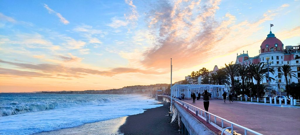 Promenade des Anglais in Nizza bei Sonnenuntergang mit Blick auf das Mittelmeer, Palmen und das Hotel Negresco