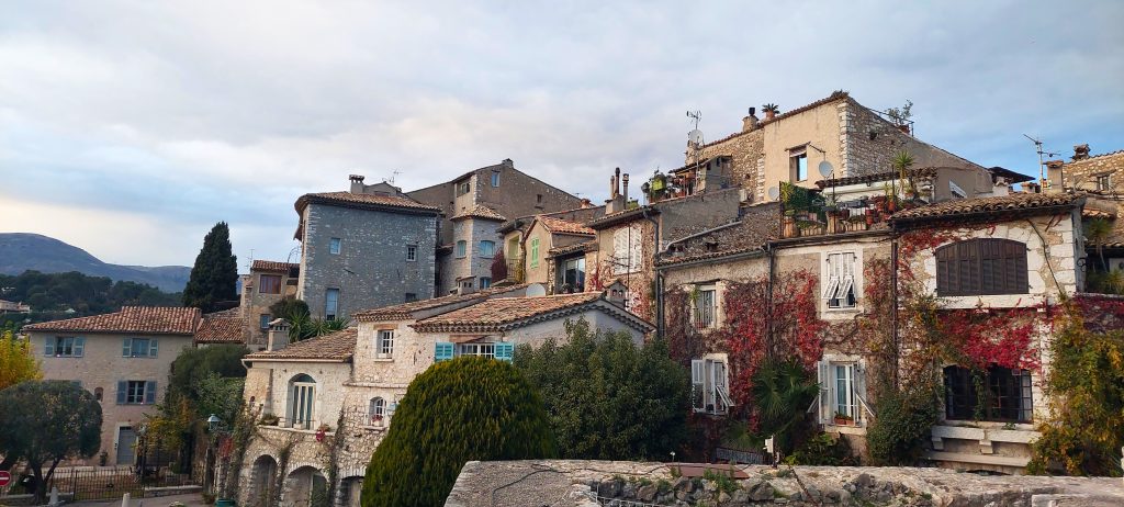 Malerische Steinhäuser von Saint-Paul-de-Vence mit mediterranen Fassaden, roten Weinranken und Blick auf die Altstadt